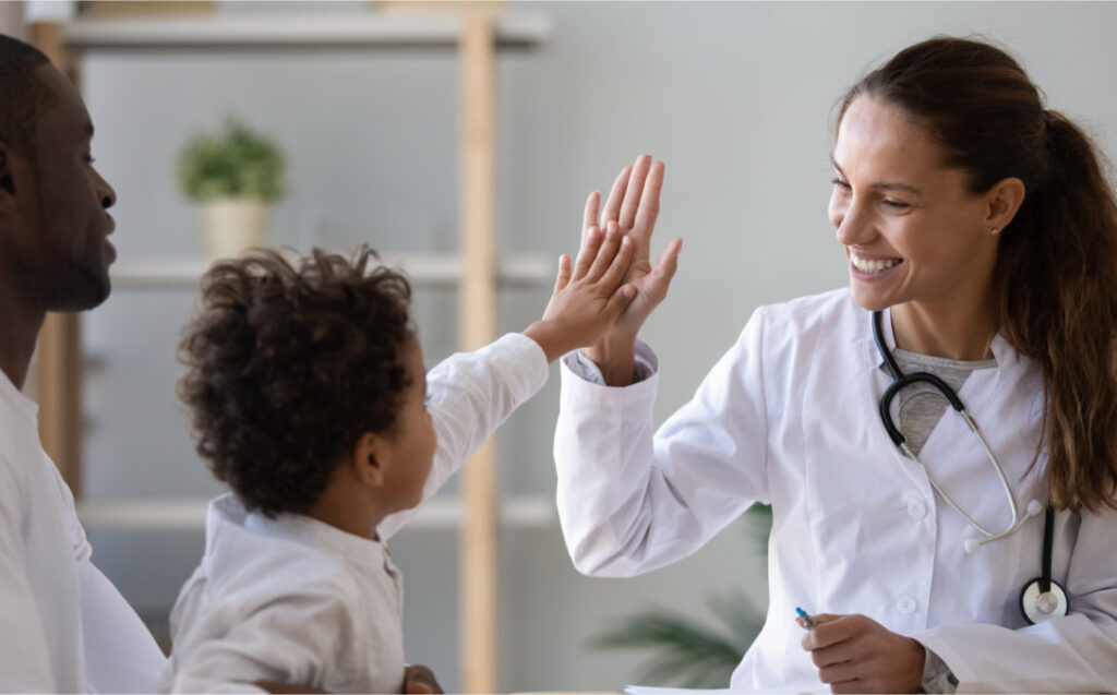 Doctor high-fiving a young patient, showcasing the impact of human-centered design in healthcare.