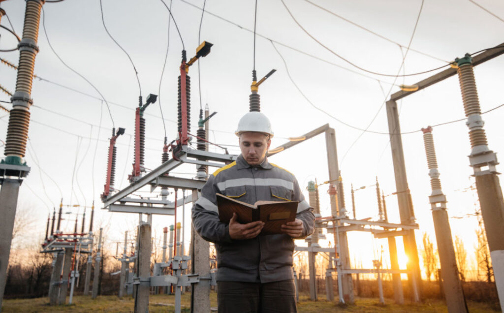Field engineer reading a manual at an energy site, using customer insights to improve sales strategy.