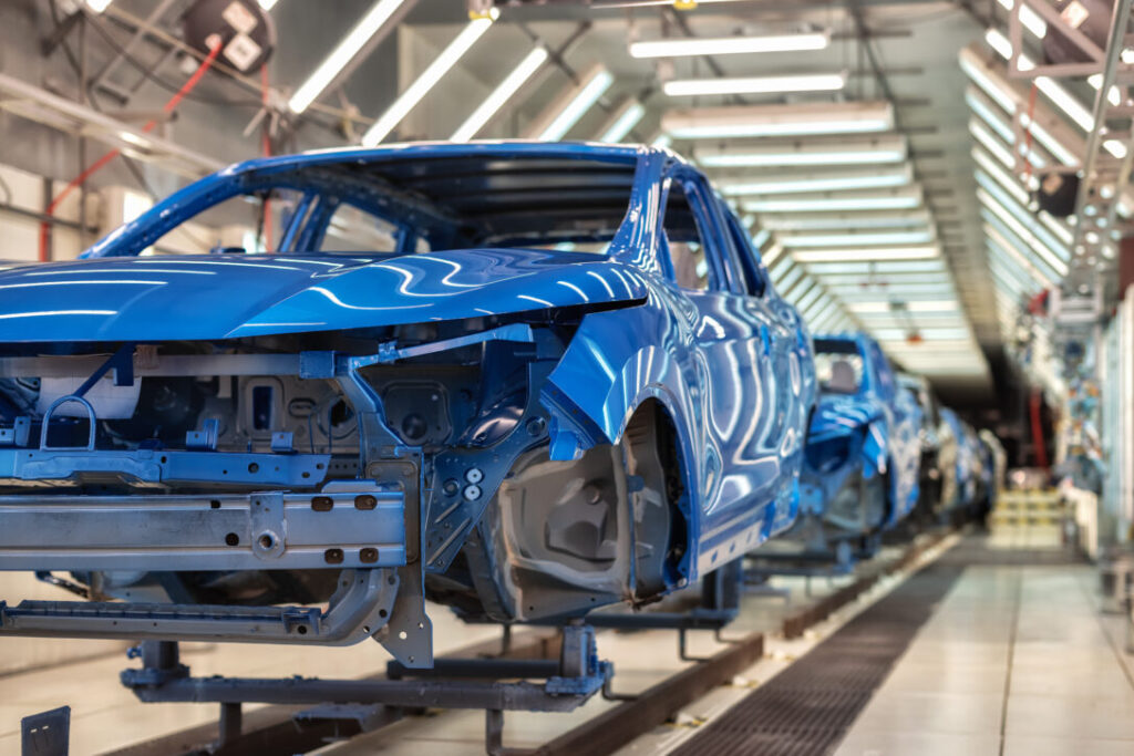 Blue cars on an assembly line in a factory, representing the impact of innovation training on the automotive industry.