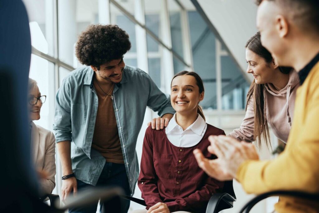 A team supports a female employee, showing how design thinking training can help improve DEI efforts and retain top talent.