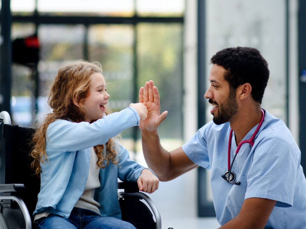 Doctor high-fiving a young patient in a wheelchair, reflecting the impact of customer-centricity in the healthcare industry.