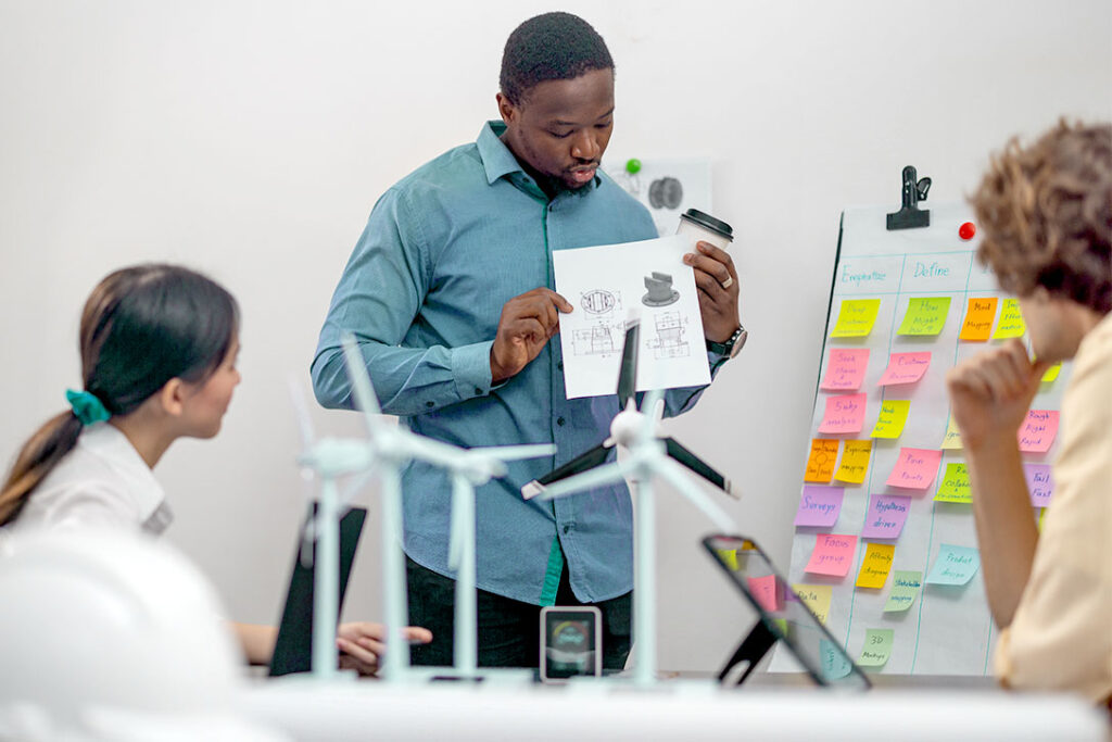 Man presenting his low-fidelity prototype to two female colleagues after conducting real user interviews.