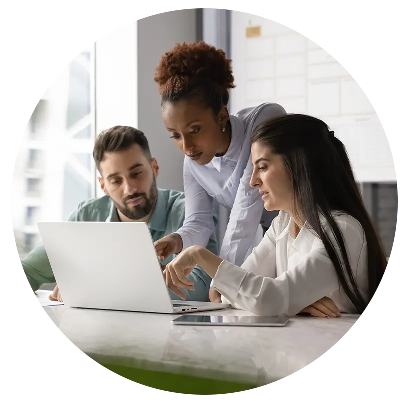 Two women and a man working on a laptop in an immersive action learning workshop.